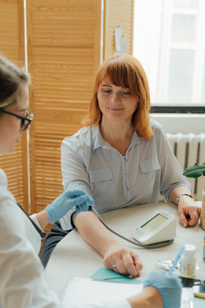 Doctor checking a patient's blood pressure using a digital monitor during a routine checkup.
